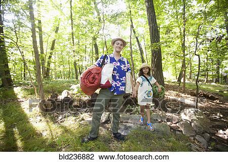 Stock Image - Caucasian father and daughter carrying bags at cabin. Fotosearch
