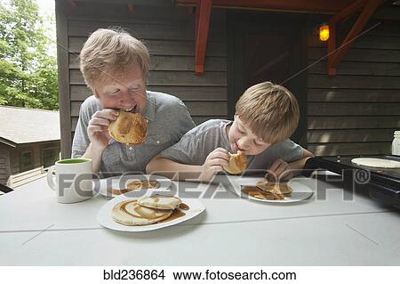 Caucasian father and son eating pancakes outdoors View Large Photo Image Picture - Caucasian father and son eating pancakes outdoors. Fotosearch