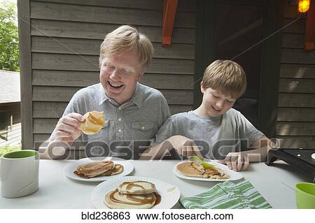 Caucasian father and son eating pancakes outdoors View Large Photo Image Stock Image - Caucasian father and son eating pancakes outdoors. Fotosearch