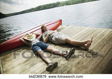 Caucasian father and son laying on wooden dock View Large Photo Image Stock Photo - Caucasian father and son laying on wooden dock. Fotosearch