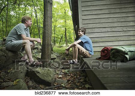 Stock Photo - Caucasian father and son talking at cabin. Fotosearch