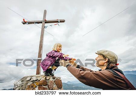 Stock Photo - Caucasian father helping daughter on rock at crucifix. Fotosearch