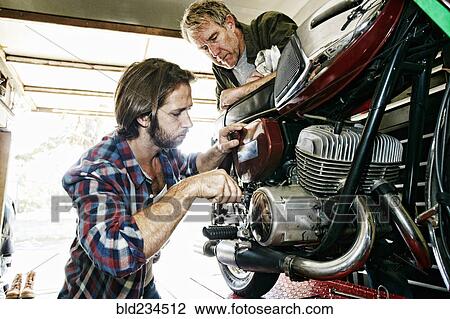 Caucasian father watching son repairing motorcycle in garage View Large Photo Image Stock Image - Caucasian father watching son repairing motorcycle in garage. Fotosearch