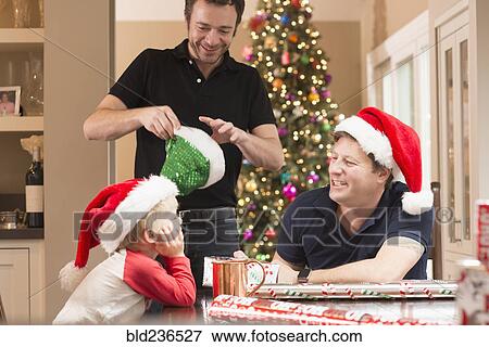 Stock Photo - Caucasian fathers and son wearing santa hats. Fotosearch