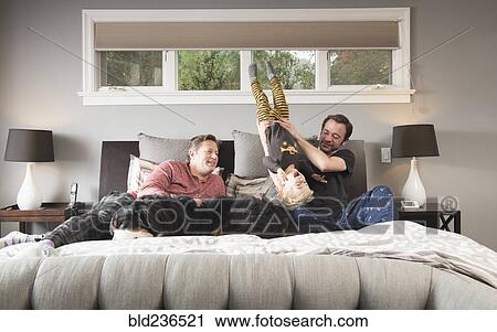 Caucasian fathers playing on bed with son and dog View Large Photo Image Stock Image - Caucasian fathers playing on bed with son and dog. Fotosearch