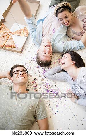 Caucasian friends laying on floor with pizza and confetti View Large Photo Image Stock Photo - Caucasian friends laying on floor with pizza and confetti. Fotosearch