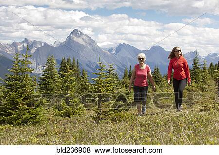 Stock Photo - Caucasian girl and grandmother walking in woods near mountain. Fotosearch