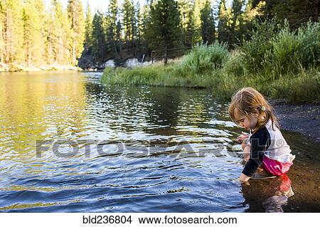 Picture - Caucasian girl crouching in river. Fotosearch