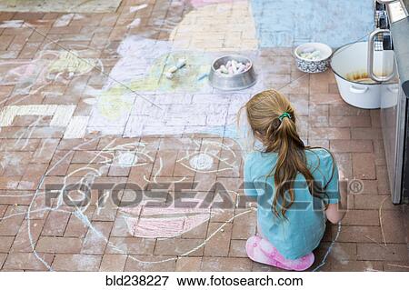 Stock Photo - Caucasian girl drawing face with chalk on patio bricks. Fotosearch