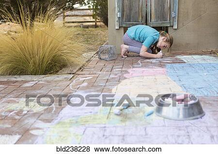Stock Photo - Caucasian girl drawing with chalk on patio bricks. Fotosearch