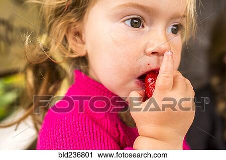 Stock Image - Caucasian girl eating strawberry. Fotosearch