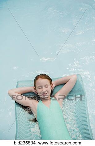 Picture - Caucasian girl floating on pool raft in swimming pool. Fotosearch