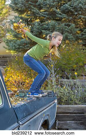 Caucasian girl holding autumn leaves jumping off truck View Large Photo Image Stock Image - Caucasian girl holding autumn leaves jumping off truck. Fotosearch