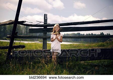 Caucasian girl holding bouquet of wildflowers leaning on wooden fence View Large Photo Image Picture - Caucasian girl holding bouquet of wildflowers leaning on wooden fence. Fotosearch