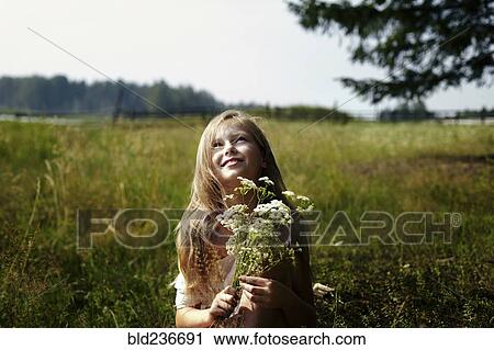Caucasian girl holding bouquet of wildflowers in field View Large Photo Image Stock Image - Caucasian girl holding bouquet of wildflowers in field. Fotosearch