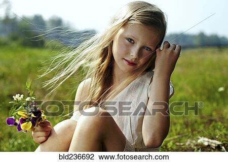 Caucasian girl holding flowers in windy field View Large Photo Image Stock Image - Caucasian girl holding flowers in windy field. Fotosearch