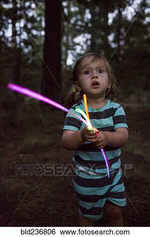 Caucasian girl holding glow sticks in forest View Large Photo Image Stock Photograph - Caucasian girl holding glow sticks in forest. Fotosearch