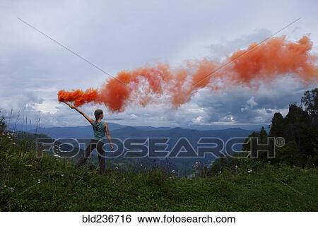 Caucasian girl holding orange smoke flare on mountain range View Large Photo Image Stock Photograph - Caucasian girl holding orange smoke flare on mountain range. Fotosearch