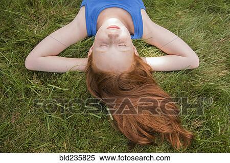 Caucasian girl laying in grass with hands behind head View Large Photo Image Stock Photography - Caucasian girl laying in grass with hands behind head. Fotosearch