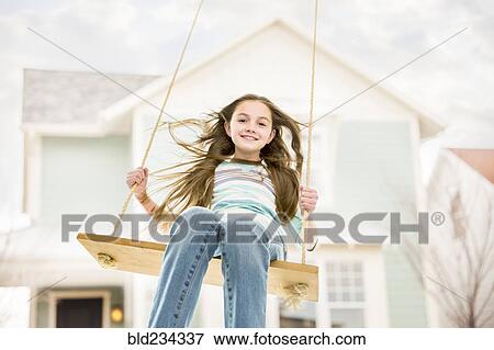 Caucasian girl on rope swing near house View Large Photo Image Stock Photo - Caucasian girl on rope swing near house. Fotosearch