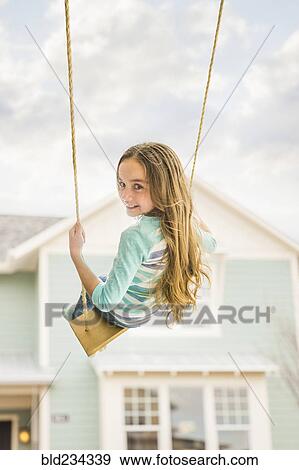 Caucasian girl on rope swing near house View Large Photo Image Stock Photo - Caucasian girl on rope swing near house. Fotosearch