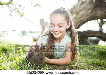 Stock Photo - Caucasian girl petting rabbit. Fotosearch