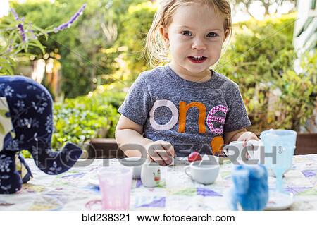 Stock Image - Caucasian girl playing with tea set. Fotosearch