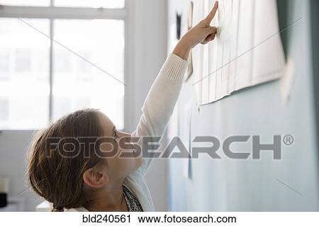 Caucasian girl pointing to paper on wall View Large Photo Image Stock Image - Caucasian girl pointing to paper on wall. Fotosearch