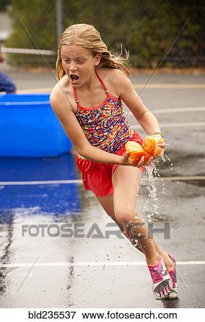 Caucasian girl running with dripping sponge in parking lot View Large Photo Image Stock Photo - Caucasian girl running with dripping sponge in parking lot. Fotosearch