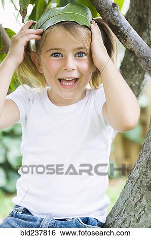 Caucasian girl sitting in tree holding leaf in hair View Large Photo Image Stock Photograph - Caucasian girl sitting in tree holding leaf in hair. Fotosearch