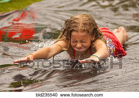 Caucasian girl sliding in water on outdoor plastic tarp View Large Photo Image Stock Image - Caucasian girl sliding in water on outdoor plastic tarp. Fotosearch