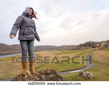 Stock Photo - Caucasian girl standing on rock in wind. Fotosearch