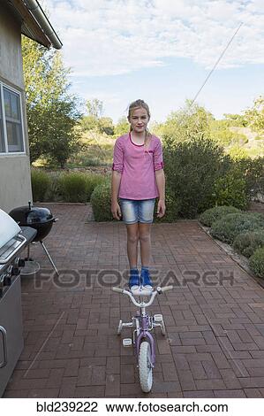 Caucasian girl standing on seat of bicycle View Large Photo Image Stock Image - Caucasian girl standing on seat of bicycle. Fotosearch
