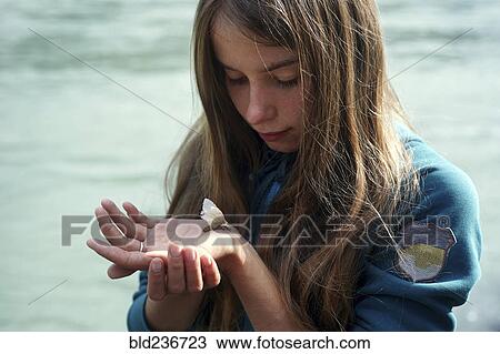 Stock Image - Caucasian girl watching moth on hand. Fotosearch