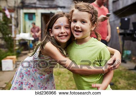 Stock Photograph - Caucasian girls hugging at backyard party. Fotosearch
