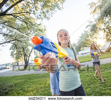 Stock Image - Caucasian girls playing with squirt guns. Fotosearch