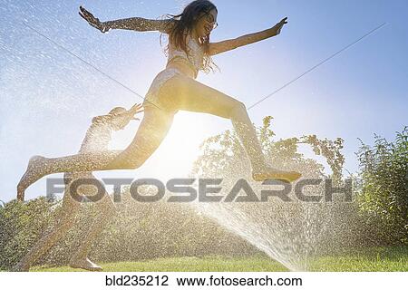 Caucasian girls running and jumping through backyard sprinkler View Large Photo Image Stock Image - Caucasian girls running and jumping through backyard sprinkler. Fotosearch