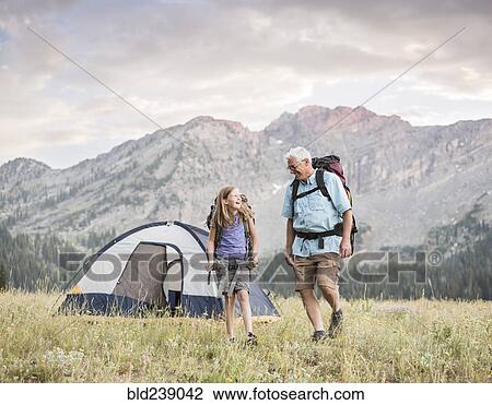 Stock Image - Caucasian grandfather and granddaughter camping on mountain. Fotosearch