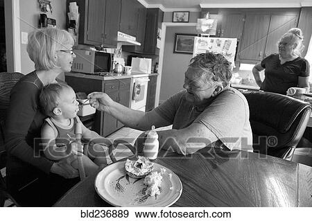 Caucasian grandfather feeding grandson in kitchen View Large Photo Image Stock Photo - Caucasian grandfather feeding grandson in kitchen. Fotosearch