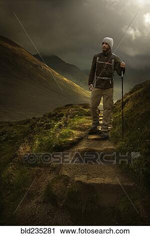Caucasian hiker holding walking stick on mountain path View Large Photo Image Stock Image - Caucasian hiker holding walking stick on mountain path. Fotosearch