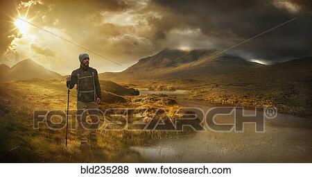Caucasian hiker holding walking stick near mountain river at sunset View Large Photo Image Stock Photo - Caucasian hiker holding walking stick near mountain river at sunset. Fotosearch