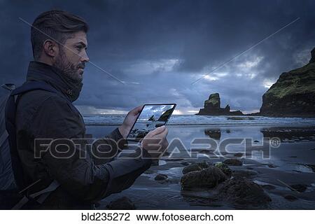 Caucasian hiker photographing beach with digital tablet at sunset View Large Photo Image Stock Image - Caucasian hiker photographing beach with digital tablet at sunset. Fotosearch