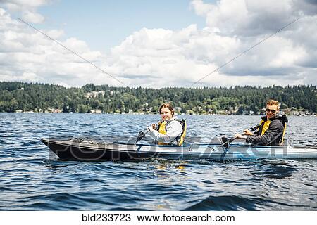 Stock Image - Caucasian man and woman paddling kayak. Fotosearch