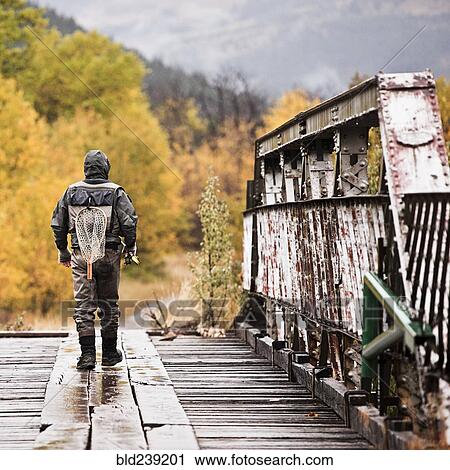 Caucasian man carrying fishing rod on bridge View Large Photo Image Stock Image - Caucasian man carrying fishing rod on bridge. Fotosearch