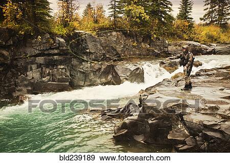 Caucasian man casting at river View Large Photo Image Stock Photo - Caucasian man casting at river. Fotosearch