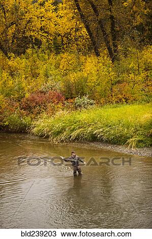 Stock Image - Caucasian man casting in river. Fotosearch