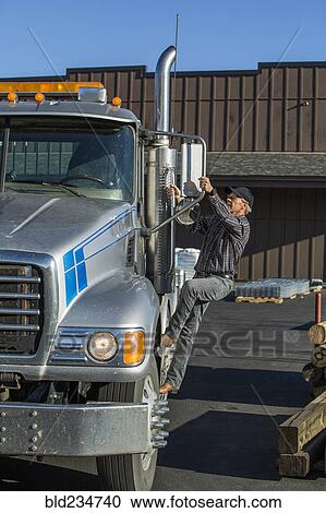 Stock Image - Caucasian man climbing into semi-truck. Fotosearch
