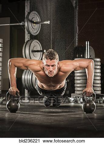 Caucasian man doing push-up using kettlebells in gymnasium View Large Photo Image Stock Image - Caucasian man doing push-up using kettlebells in gymnasium. Fotosearch