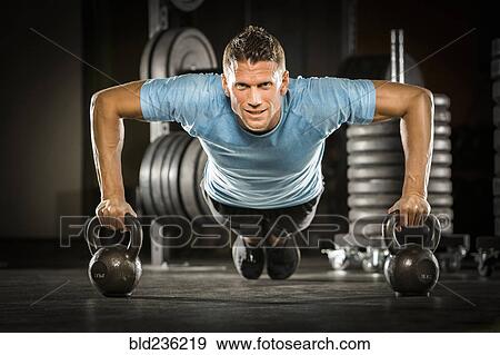 Caucasian man doing push-up using kettlebells in gymnasium View Large Photo Image Stock Photo - Caucasian man doing push-up using kettlebells in gymnasium. Fotosearch