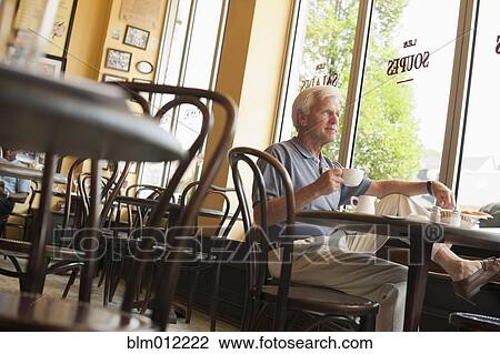 Stock Image - Caucasian man drinking coffee in restaurant. Fotosearch